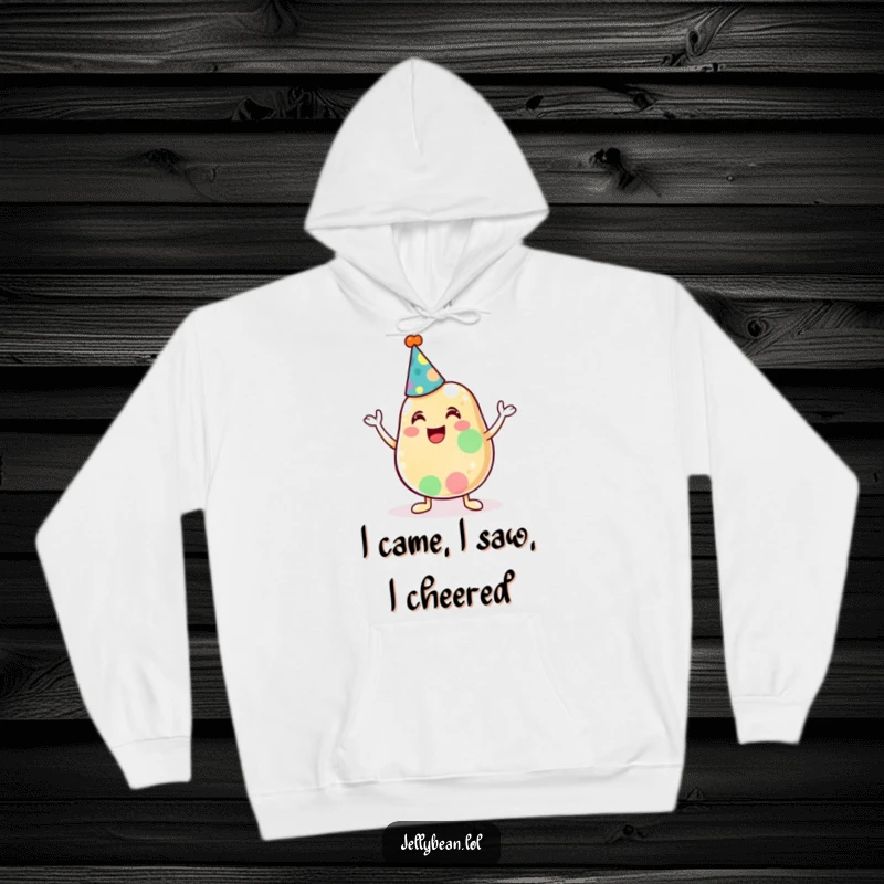 Funny hoodie displaying an anthropomorphic jelly bean in a party hat, enthusiastically cheering for a joyous occasion.